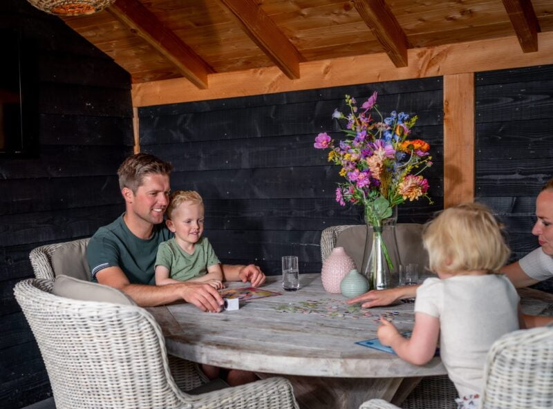 Douglas kapschuur 5 Douglas veranda met gezin aan tafel die spelletje doen