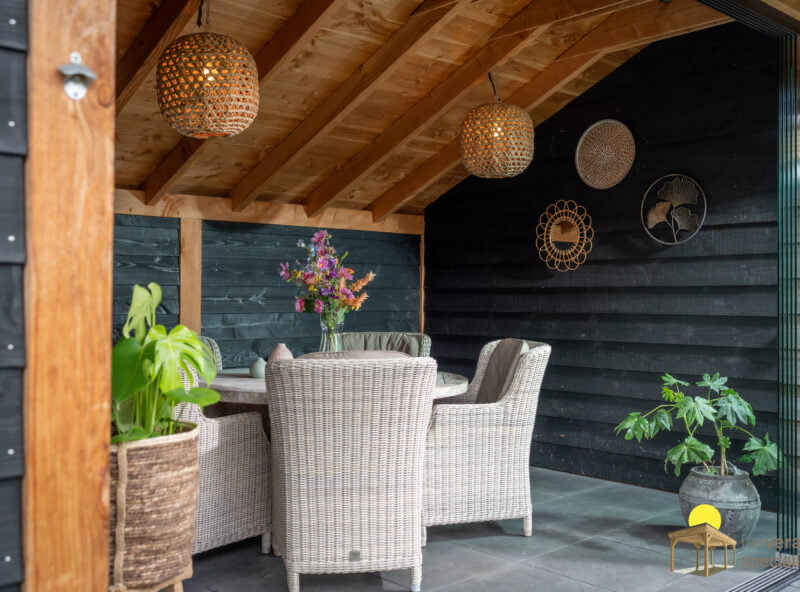 houten kapschuur 6 Zwart houten kapschuur met rieten meubilair