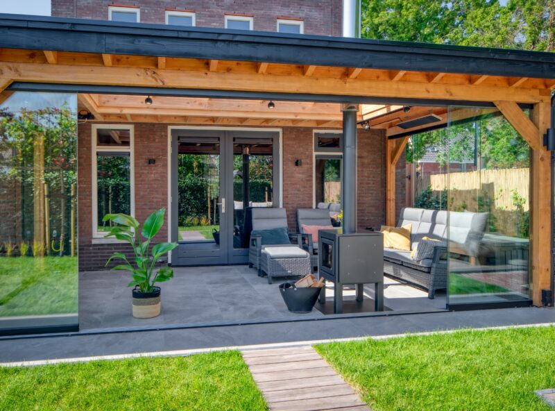 Overkapping aan huis 6 Overkapping aan huis met glazen schuifwand en houtkachel