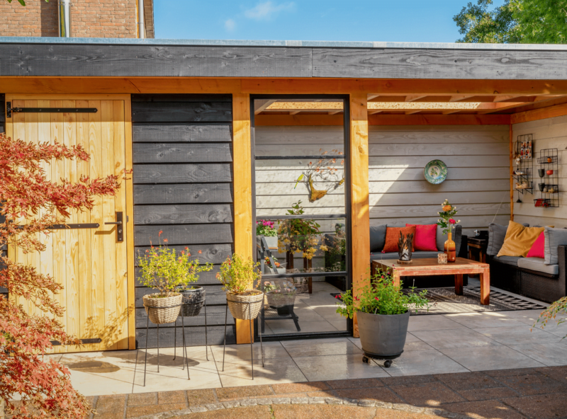 Tuinhuis met overkapping 2 Tuinhuis met overkapping en veel planten in de tuin